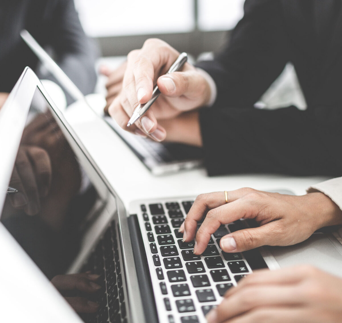 Two people with laptop computers collaborating on a project. This image illustrates an article on Corporation Tax services from THP Chartered Accountants.
