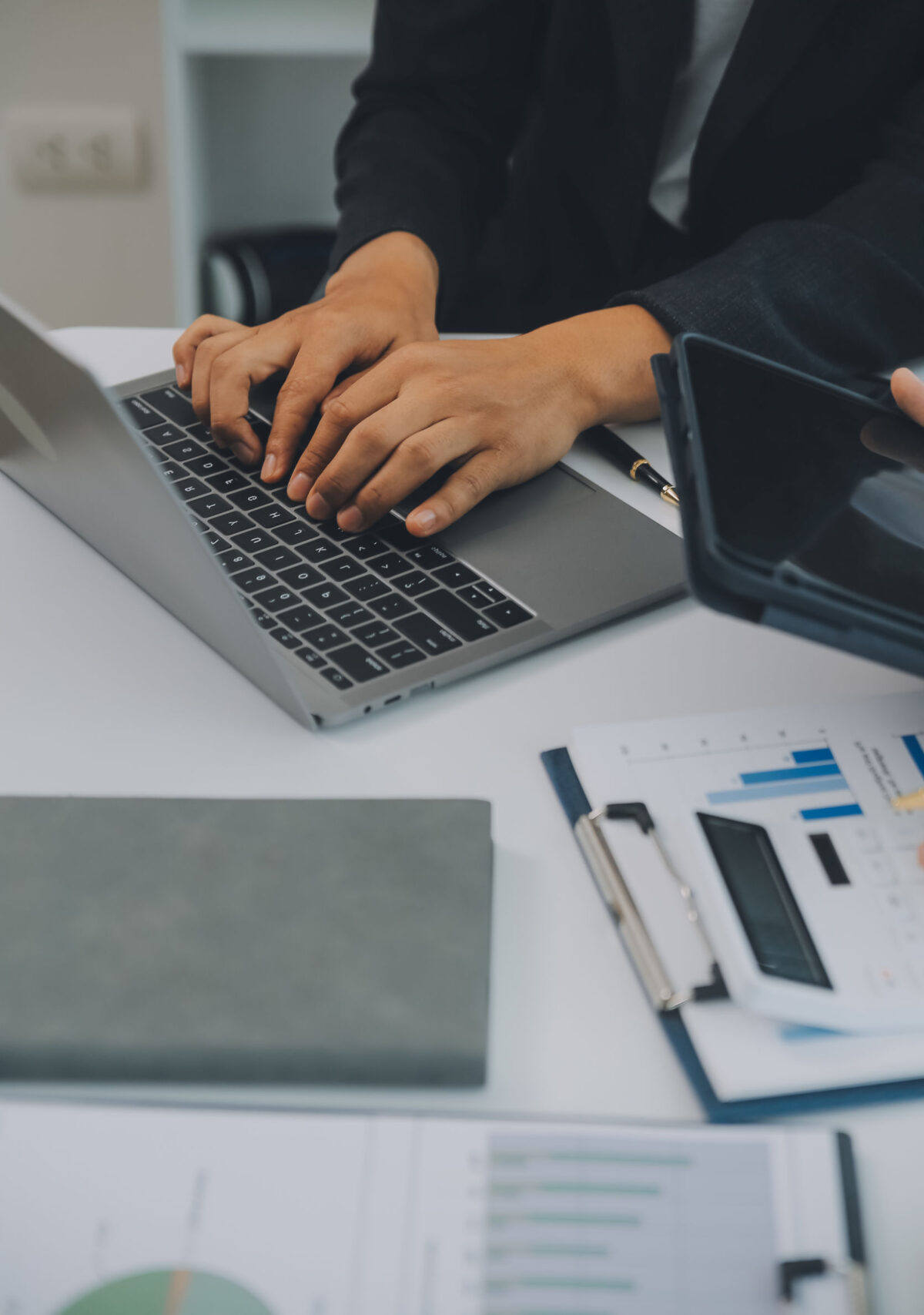 Image of someone working on a laptop, with a calculator and printed financial figures.