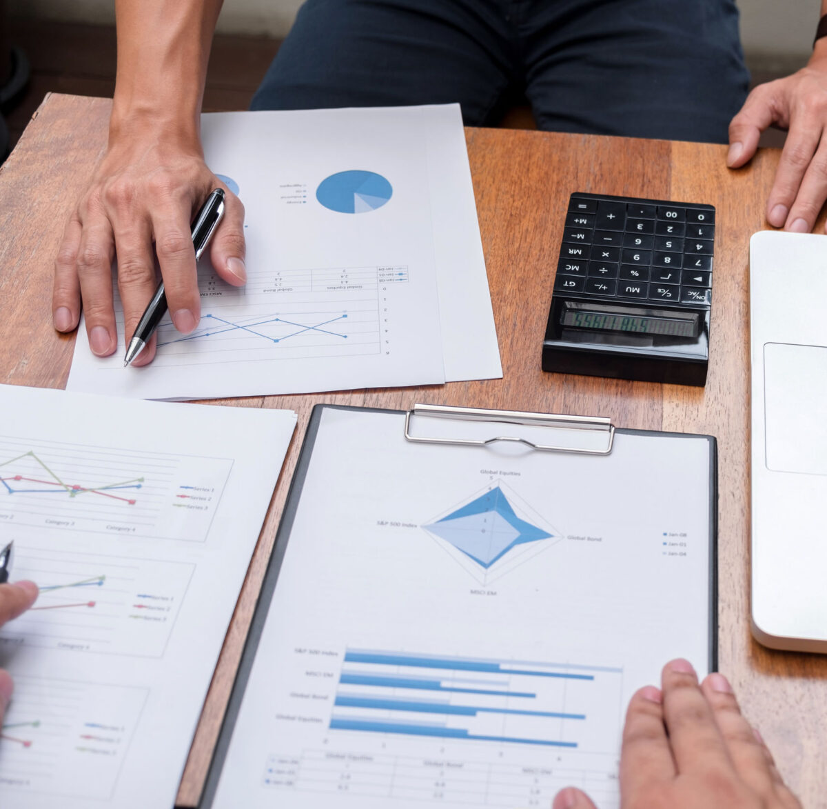 An image of two people's hands. They are working on financial figures and using a calculator. This illustrates a page that talks about THP's management accounts service.