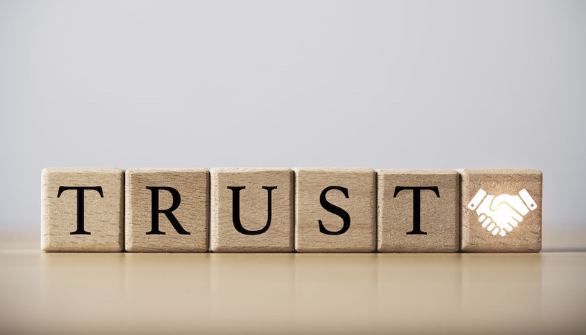 Wooden blocks spelling out the word TRUST. An illustration for an article about AEOI compliance