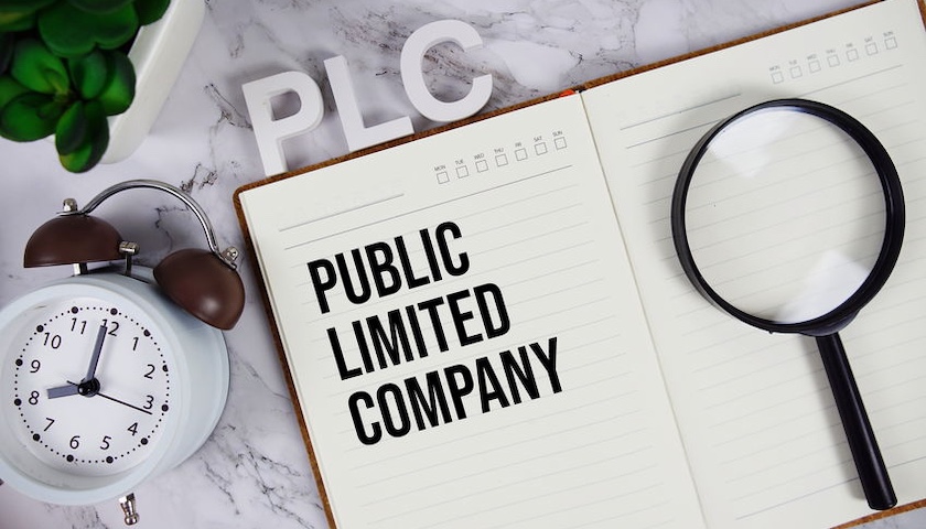 An image of a notebook displaying the words Public Limited Company, with the letter PLC above it and a magnifying glass on it - to illustrate an article on becoming a PLC