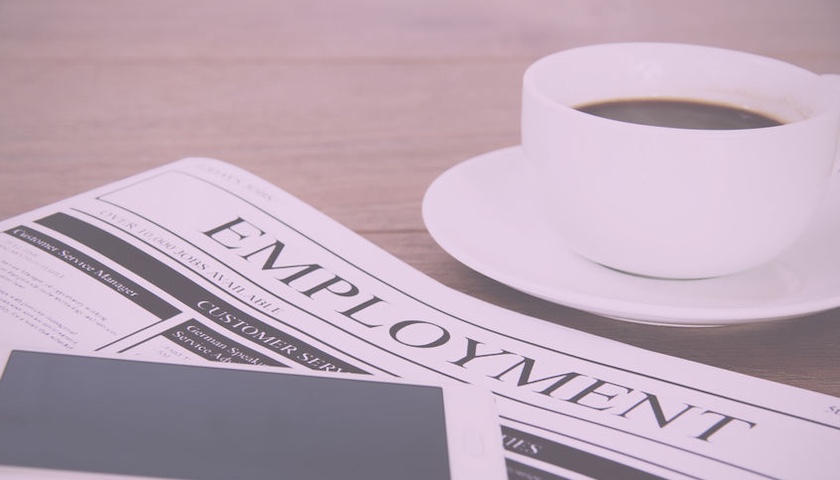 A picture of a cup of coffee, a phone and a newspaper with a masthead reading EMPLOYMENT - to illustrate an article on the Employment Rights Act 2025.