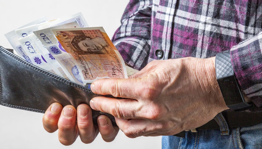 Image of a man putting UK currency into a wallet - to illustrate an article on Statutory Sick Pay changes 2026
