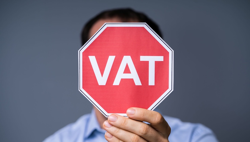 Man holding a red sign that reads VAT - to accompany an article on VAT partial exemption