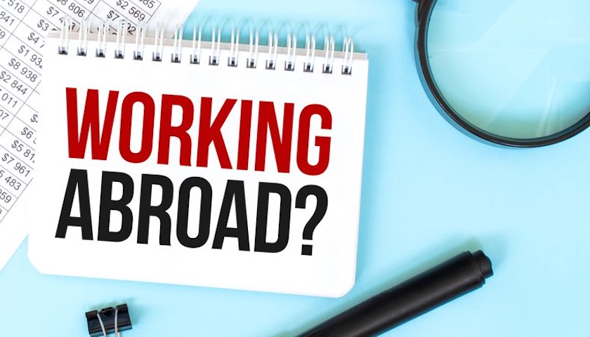 Image of the words 'WORKING ABROAD' on a notepad, illustrating and article on remote work overseas.