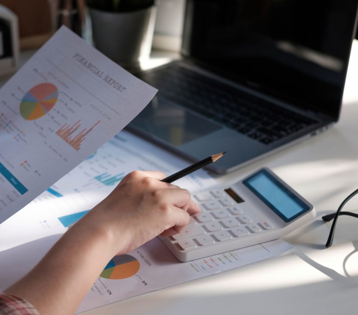 You'll be supported by our wider tax planning team An image of someone using a calculator and laptop to work on financial figures, illustrating a section on who is responsible for delivering THP's tax planning services.