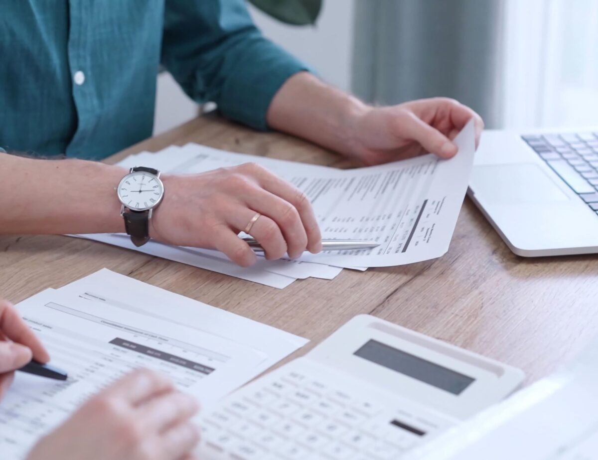 Image of two people working with a laptop, calculator and financial data - illustrating a service page on Tax Planning Services