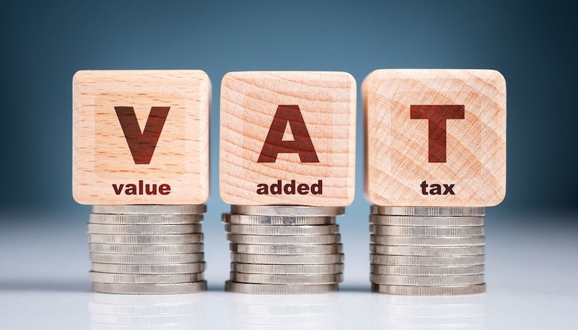 The words VAT / Value Added Tax written on wooden blogs, resting on piles of coins - to illustrate an article on the VAT Cash Accounting scheme.