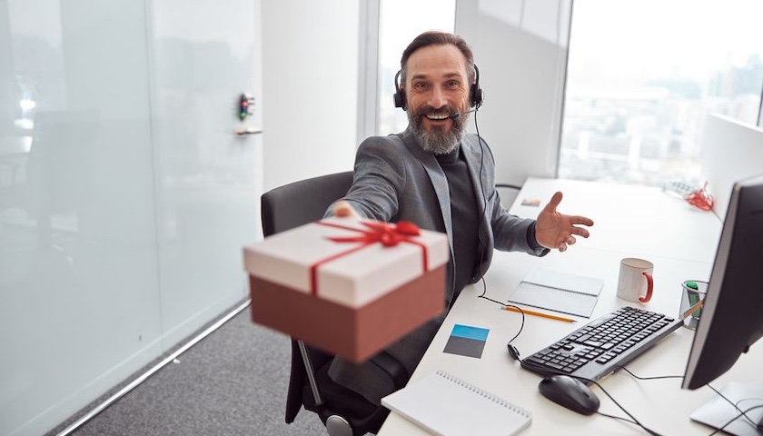 Smiling office worker holding out a wrapped gift - illustrating an article on PAYE settlement agreements