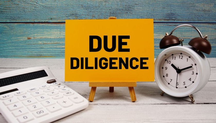 Image of the words 'DUE DILIGENCE' on a miniature noticeboard next to an alarm clock and a calculator - illustrating a Financial Due Diligence Checklist article