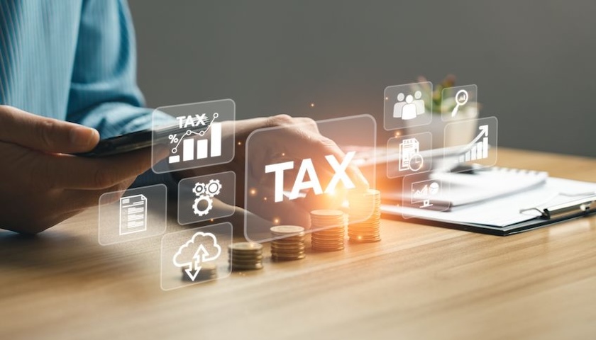A concept image of the word TAX overlaid on someone using a phone - to illustrate an article on how people who haven't signed up for MTD could be signed up automatically by HMRC