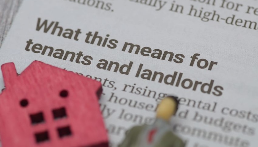 Image of a model house and person on a newspaper with a header 'What this means for tenants and landlords' - illustrating an article on the landlord register in England