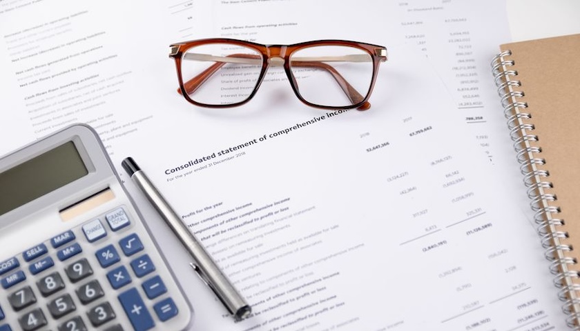 Image of spectacles and a calculator on some printed accounts, for an article on dormant company accounts