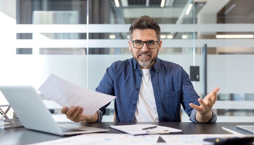 Stressed looking businessman at a desk, possibly having made an overpayment of wages