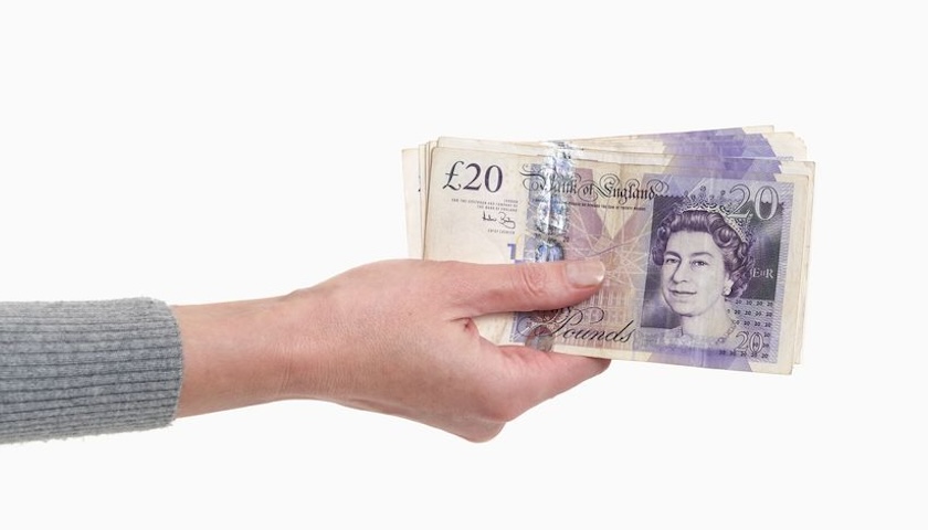 A photo of a hand offering some cash, for an article on VAT on deposits.